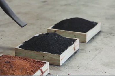 Trays of coal fines and soils under a spray hose.
